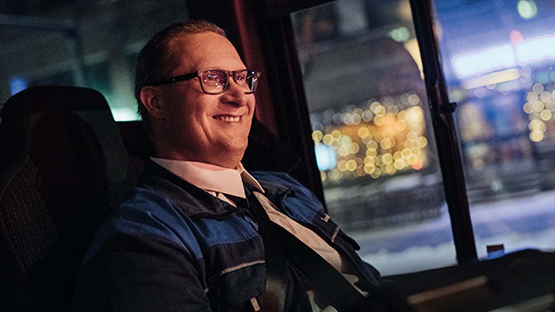 Bussikuski ajaa ja hymyilee mustat silm&auml;lasit kasvoillaan